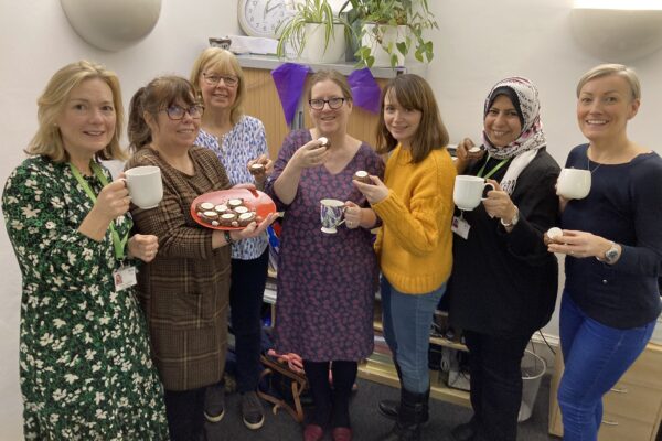 A group featuring 7 of Kindred's staff having a cuppa and offering cakes