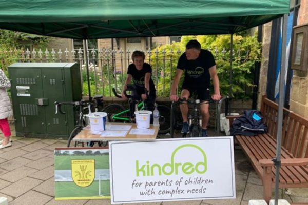 Two people on stationary bikes peddling for a Kindred fundraiser